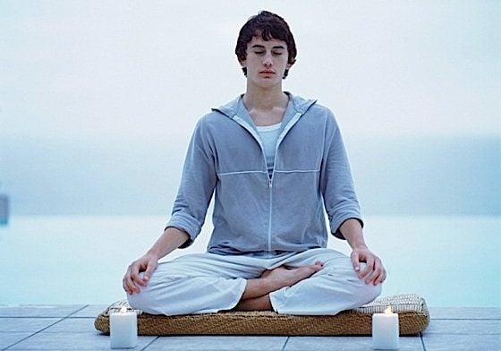 A man in lotus posture meditating on a dock.