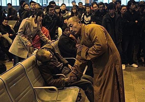 A monk holds the hand of a deceased person found on a train platform in China. 