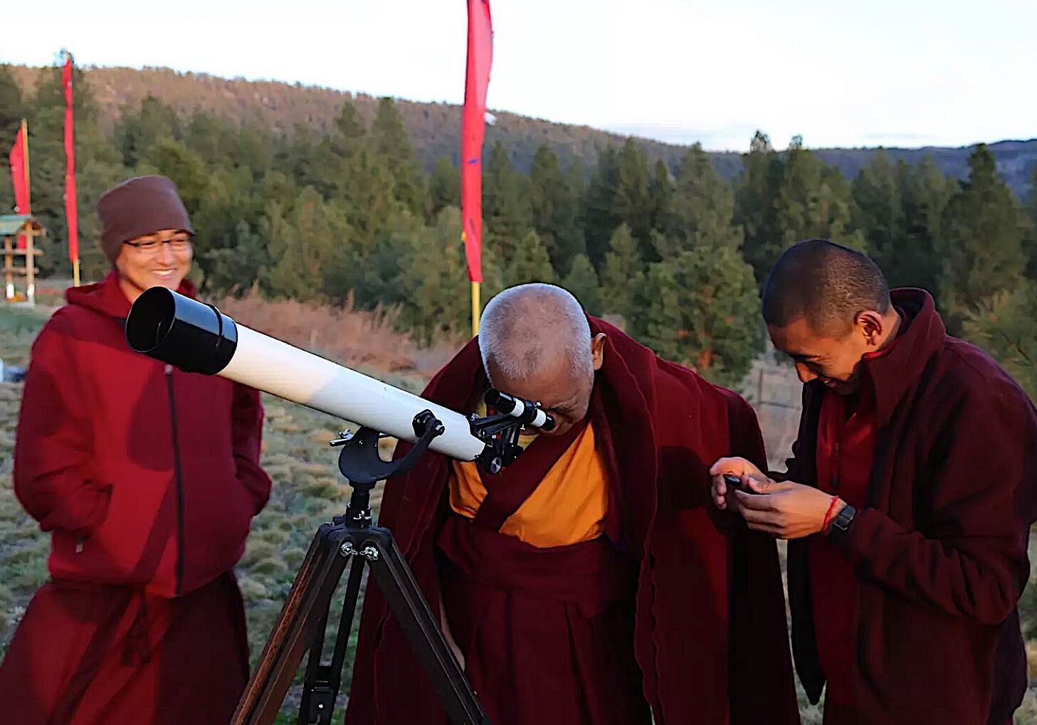 Lama Zopa Rinpoche gazes through a telescope. FPMT.