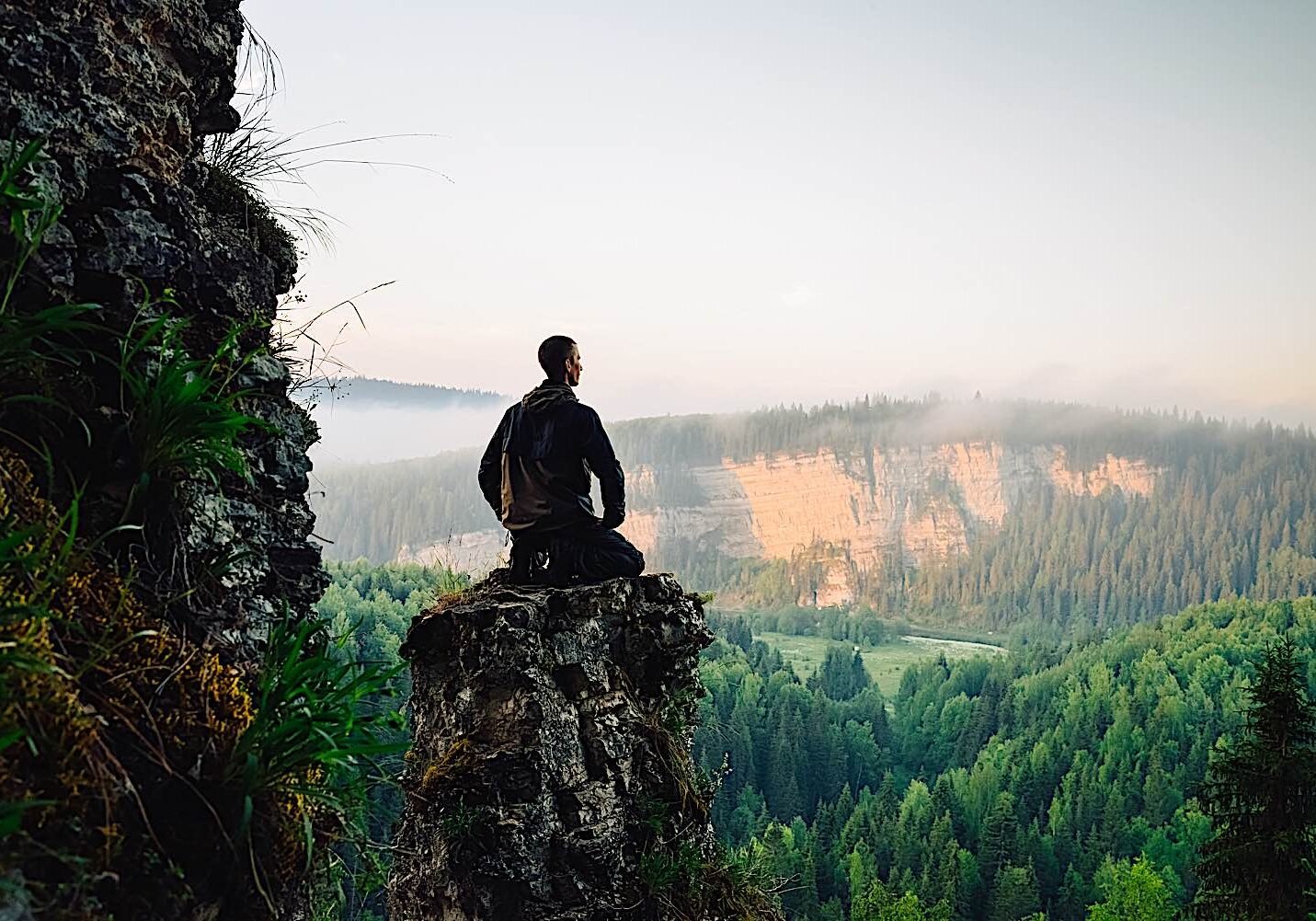 A man meditates in nature. Meditaiton has 10 recognized health benefits based on research.