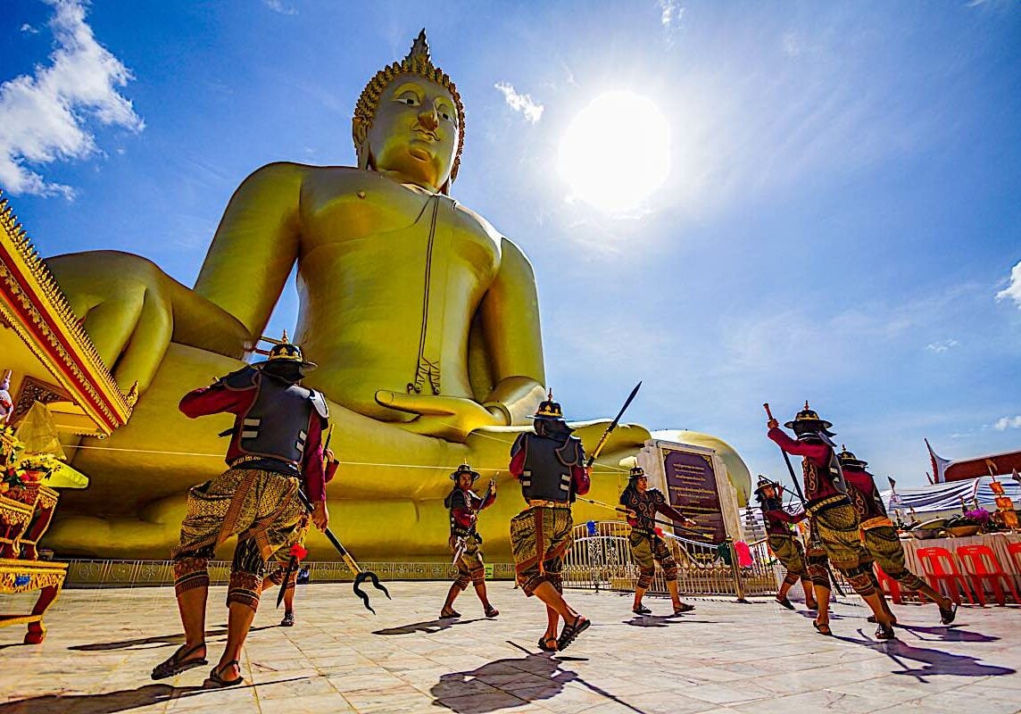 Angthong, Thailand - July 15, 2014: Actors performing fighting in ancient warrior style in front of large golden Buddha Image to celebrate Buddhist event at Wat Muang, Buddhist temple in Angthong, Thailand.